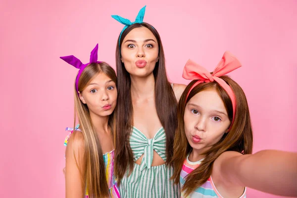 Close up foto de irmãs mais velhas mais jovens com headbands fazer selfie enviar beijos de ar usando vestidos saia isolada sobre fundo rosa — Fotografia de Stock