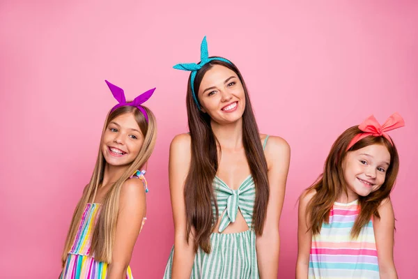 Retrato de charmoso três meninas posando com radiante lindo sorriso vestindo capas brilhantes saia vestido isolado sobre fundo rosa — Fotografia de Stock