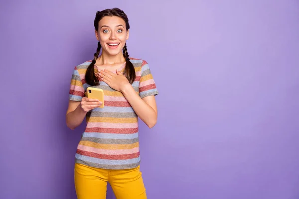 Ritratto di eccitato divertente ragazza uso social network sul suo smartphone leggere meravigliosi blog ottenere notifica urlo wow omg indossare giallo vestito moderno isolato colore viola sfondo — Foto Stock