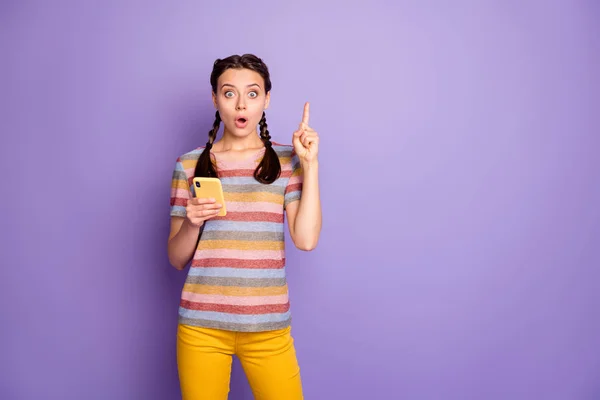 素晴らしい10代の100万人の女の子はスマートフォンを使用してアイデアを得る何を投稿ソーシャルメディアネットワークを上げるインデックス指悲鳴信じられないほどの摩耗黄色のズボンの服孤立紫色の背景 — ストック写真