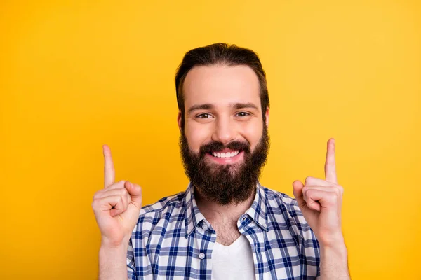 Gros plan portrait de son il agréable joyeux gai gai gars barbu confiant en chemise à carreaux pointant deux index vers le haut annonce isolée sur brillant vif fond de couleur jaune vif — Photo