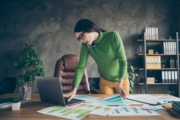 Foto di business signora parla telefono partner società start-up investimento guardare carte statistiche controllare le informazioni notebook usura verde dolcevita giallo pantaloni ufficio moderno — Foto Stock