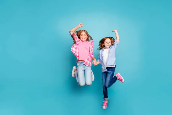 Ganzkörpergröße Foto von zwei jubelnden ermutigt aufgeregte freie Mädchen springen, während isoliert mit blauem Hintergrund — Stockfoto