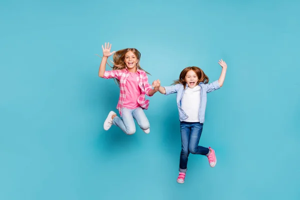 Ganzkörpergröße Foto von zwei aufgeregt fröhlich überglücklich optimistisch Mädchen tragen Jeans Denim weiß, während isoliert mit blauem Hintergrund — Stockfoto