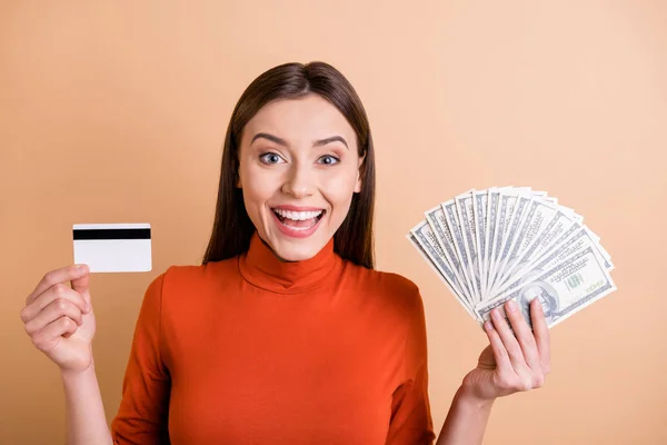 Foto av glada charmiga söta vackra affärskvinna visar dig två betalningssätt samtidigt ler tandlöst bär polotröja isolerad pastell beige färg bakgrund — Stockfoto