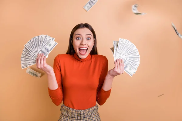 Portrait of her she nice attractive lovely cheerful cheery crazy glad straight-haired girl holding throwing large sum of money budget isolated over beige pastel color background — Stock Photo, Image