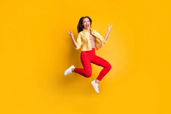 Volledige lengte lichaamsgrootte draaide foto van vrolijke schreeuwende vrouw tonen gehoornde vingers rock teken in rode broek dragen witte schoenen geïsoleerde levendige kleur achtergrond — Stockfoto