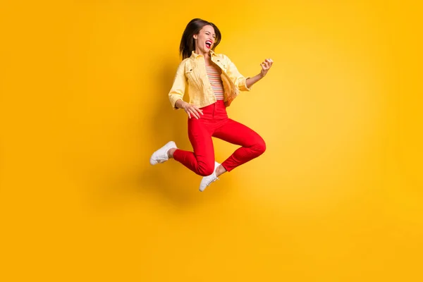 Cuerpo de cuerpo entero suze convertido foto de alegre grosero excitado loca alegre mujer regocijándose en saltar jugando imaginar guitarra en pantalones rojos aislado color vivo fondo —  Fotos de Stock