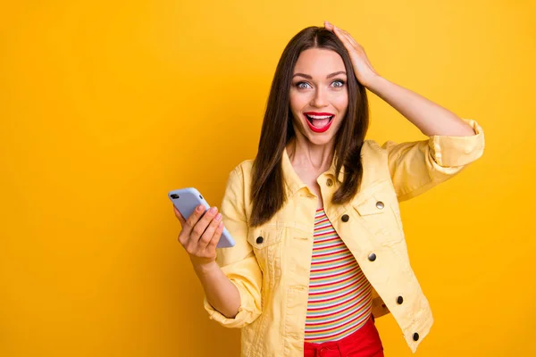 Photo of excited cute cheerful girlfriend holding her head when typing messages to friends with gadget screaming emotionally isolated vivid color background — Stock Photo, Image