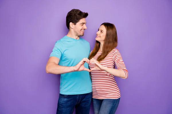 Photo de charmant couple faisant mains doigts coeur figure célébrant amoureux jour sentiments tendres porter tenue décontractée t-shirts bleu rayé jeans isolé couleur pourpre fond — Photo