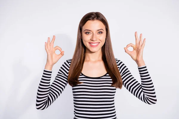 Retrato de la encantadora dama mostrando signo ok mirando con sonrisa radiante usando suéter a rayas aislado sobre fondo blanco — Foto de Stock