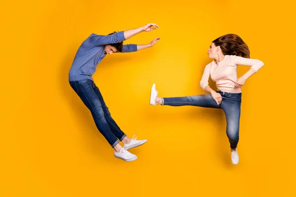 Άντρας εναντίον γυναίκας. Δύο άνθρωποι ninja πλήρους μεγέθους φωτογραφία έχουν kickboxing καράτε προπόνηση αγώνα κλωτσιά πόδια τύπος χάνουν πτώση φορούν τζιν τζιν απομονώνονται σε κίτρινο χρώμα φόντο — Φωτογραφία Αρχείου