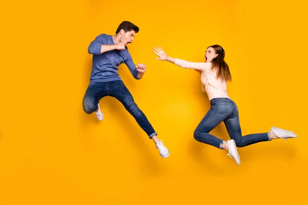Celotělová fotografie dvou ninja žena muž mají boj skok kop nohy ruce pocit bláznivé oblečení růžová modrá svetr džíny tenisky izolované přes žlutou barvu pozadí — Stock fotografie