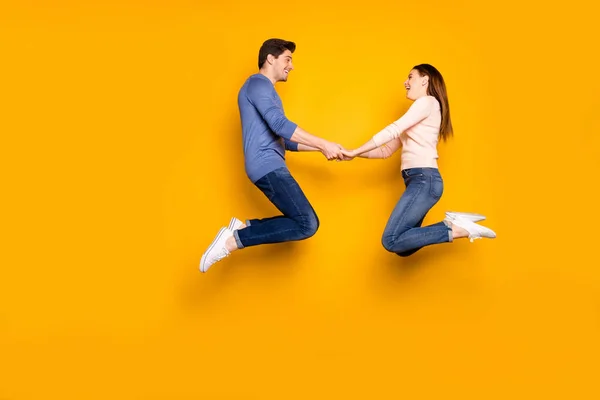 Helkroppsprofil sida foto av funky två studenter gifta människor hoppa slappna av vila hålla handen känna glädje känslor bära blå rosa outfit sneakers isolerade över gul färg bakgrund — Stockfoto