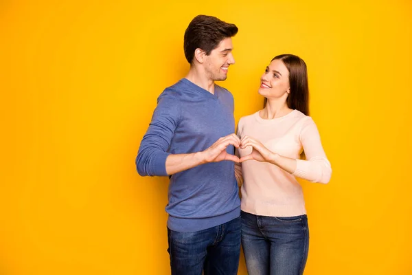 Αγάπη για πάντα έννοια. Τρυφερή παθιασμένη αγκαλιά δύο συζύγων κάνουν το δάχτυλο της καρδιάς να φαίνεται υποστήριξη φορούν μοντέρνα στολή τζιν τζιν απομονωμένο σε κίτρινο χρώμα φόντο — Φωτογραφία Αρχείου