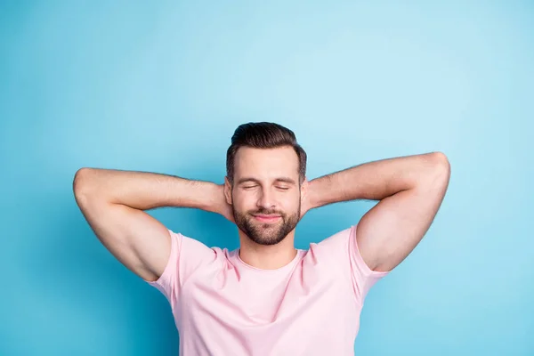 Foto von attraktiven Kerl hält die Hände hinter dem Kopf Augen geschlossen genießen erstaunliche Wochenende Tag entspannend tragen lässig rosa T-Shirt isoliert blaue Farbe Hintergrund — Stockfoto