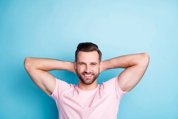 Foto de chico atractivo cogido de la mano detrás de la cabeza disfrutar de un increíble día de fin de semana relajante momento de refresco usar casual rosa camiseta aislada de color azul de fondo — Foto de Stock