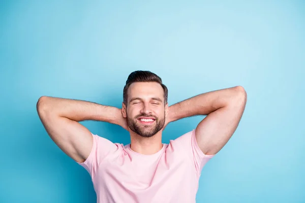 Foto av attraktiv kille som håller händerna bakom huvudet ögonen stängda njuta av fantastiska helg dag avkopplande slitage casual rosa t-shirt isolerad blå färg bakgrund — Stockfoto