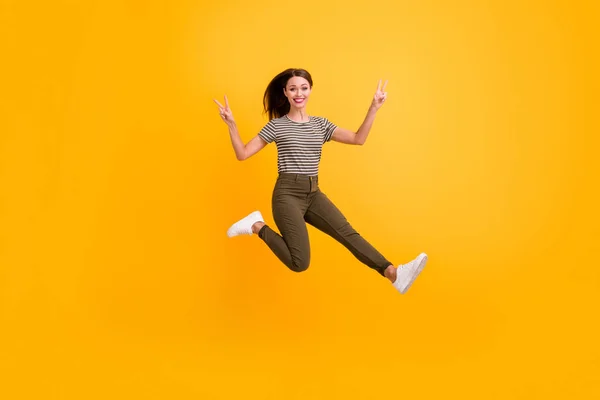 Foto in voller Größe von fröhlichen verspielten Mädchen springen entspannen Frühling freie Zeit machen V-Zeichen tragen gut aussehende Kleidung isoliert über Glanz Farbhintergrund — Stockfoto