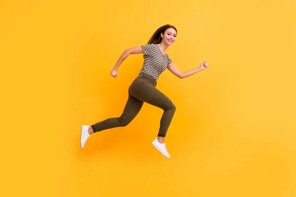Foto lateral de perfil de tamaño completo de emocionada chica entusiasta salto correr rápido sentir contenido emociones francas usar ropa elegante aislado sobre fondo de color amarillo —  Fotos de Stock