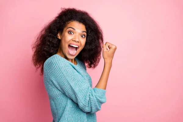 Foto de moda alegre rizado ondulado bastante dulce mujer expresando emociones alegres en la cara de pie lado perfil haciendo puño aislado pastel color fondo — Foto de Stock