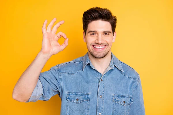 Porträtt av positiva glada kille promotor visa okej tecken råda promo annonser bära casual stil kläder isolerad över gul färg bakgrund — Stockfoto