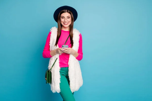 아주 현대적 인 스타일의 미인 여행자의 사진 전화 채팅 친구를 들고 기분좋은 여행 기분좋은 모자 모자 모자 바지를 입고 핑크 점퍼외로운 푸른 배경 — 스톡 사진