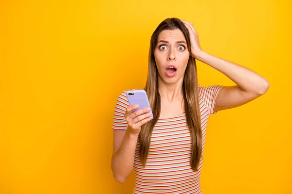 Fotografie nemluvné hezká dáma držet telefon ruce čtení špatné zprávy kontrola následovníci paže na hlavě nosit příležitostné pruhované tričko izolované žluté barvy pozadí — Stock fotografie