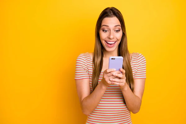 Foto de la señora bonita divertida sostener las manos del teléfono leyendo buenas noticias comprobar seguidores suscriptores sorpresa desgaste casual rayas camiseta aislado color amarillo fondo — Foto de Stock