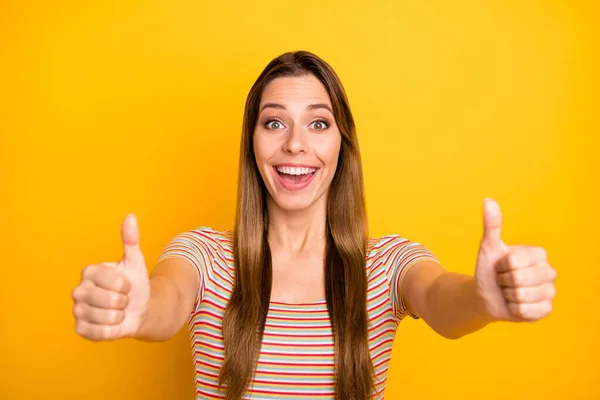 Closeup photo of amazing lady holding raised thumb fingers up expressing agreement good products quality wear casual striped t-shirt isolated yellow color background — Stock Photo, Image