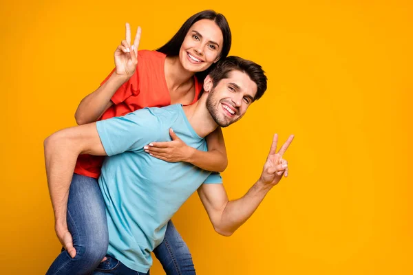 Foto de perfil del tipo que lleva aventuras de verano de señora a cuestas junto mostrando símbolos de signo v usan casual elegante azul naranja camisetas vaqueros aislados color amarillo fondo —  Fotos de Stock