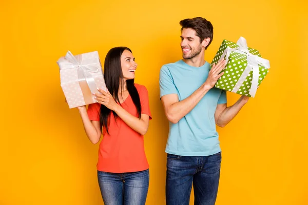 Photo of two funny guy lady people holding hands big giftboxes looking eyes thankful wear casual trendy blue orange t-shirts jeans isolated yellow color background — 스톡 사진