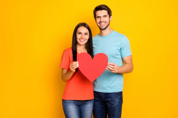 Photo of amazing two people guy lady celebrating valentine day holding red paper heart figure shape wear casual blue orange t-shirts isolated yellow color background — 스톡 사진