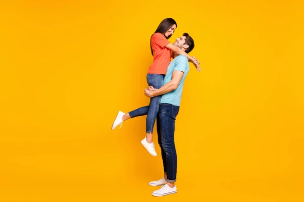Full tělo foto dvou roztomilých lidí pár chlap drží nosit Lady vypadat oči krásný víkend romantika moment nosit ležérní modrá oranžová trička džíny izolované žluté barvy pozadí — Stock fotografie