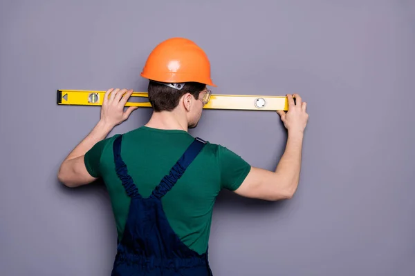 Belakang melihat foto pekerja maskulin tampan insinyur terampil mengukur panjang rak dinding memakai kaus keamanan bawah tanah helm pelindung terisolasi latar belakang abu-abu — Stok Foto
