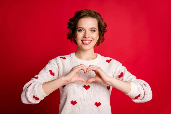 Retrato de positivo alegre namorada mostrar mãos peito coração apaixonado amor sinal desfrutar de amour desgaste moderno pulôver isolado sobre vermelho brilhante cor fundo — Fotografia de Stock