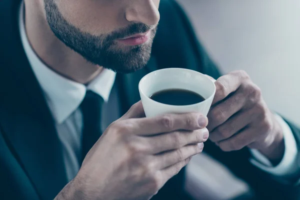 成功したビジネス男のクロップ写真手コーヒー飲料マグカップを保持快適な匂いを楽しむ黒ブレザーシャツネクタイスーツ衣装椅子室内に座っているオフィス — ストック写真