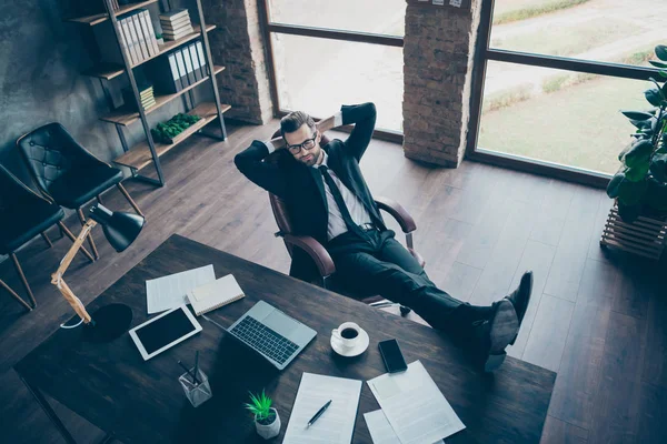 Ângulo alto acima ver foto de cara de negócios bonito beber café relaxante quebrar pernas na mesa olhando notebook tela desgaste especificações blazer preto camisa calças gravata terno sentar cadeira escritório dentro de casa — Fotografia de Stock