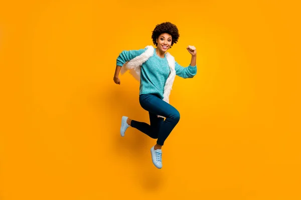 Full size foto van gekke grappige funky afro Amerikaanse meisje springen run haast dragen wit turquoise trui herfst blauw stijlvolle trendy outfit geïsoleerd over helder gele kleur achtergrond — Stockfoto