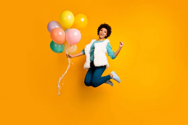 Full length photo funky crazy afro american girl jump hold balons win event scream yes raise fists wear white teal stylish trendy sweater blue pants trousers isolated bright color background — 스톡 사진