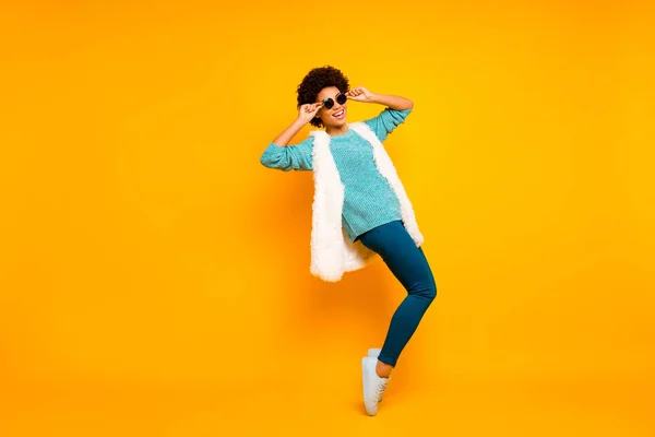 Full size photo of cheerful afro american girl feel crazy dance dancer on night club clubber touch sunglass wear blue white teal pullover trousers isolated yellow color background — 스톡 사진