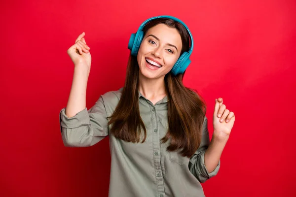 Foto de atractiva dama humor alegre tecnología moderna auriculares en las orejas escuchar nueva canción popular de la juventud desgaste casual gris verde camisa aislado color rojo fondo — Foto de Stock