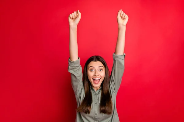 Photo of attractive funny lady raising fists up supporting friends in sports competition cheerleader cheerful wear casual grey green shirt isolated red color background — 스톡 사진