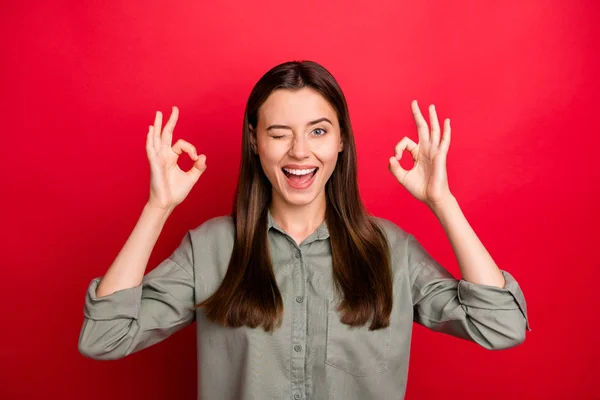 Primer plano retrato de ella ella agradable atractivo bastante alegre alegre alegre chica de pelo recto en camisa de color caqui que muestra dos ok-signo guiño aislado sobre brillante brillo vivo vibrante fondo de color rojo — Foto de Stock