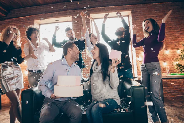 Foto do grupo melhores amigos fazer festa do bebê surpresa aniversário de casamento futuros pais sentar sofá segurar grande bolo beijando confete queda desgaste formalwear loft dentro de casa — Fotografia de Stock