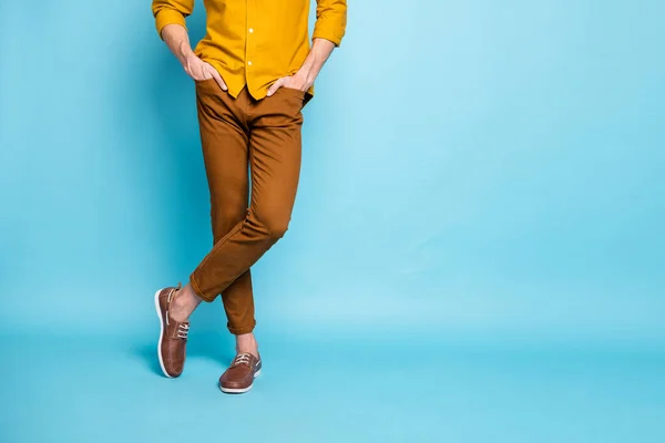 Foto recortada de pernas de homem confiante em calçado cruzado com as mãos em bolsos de pé confiantemente isolado sobre fundo cor pastel — Fotografia de Stock