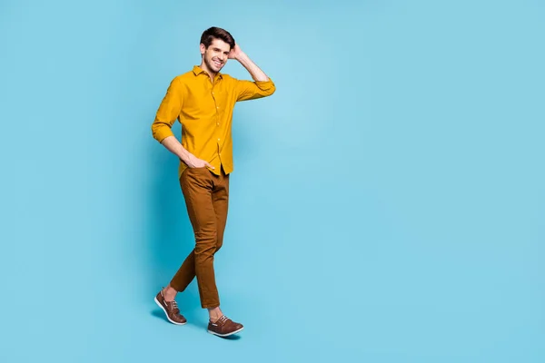 Otočený foto pohledný chlap drží ruku v kapse kalhot drží své vlasy na sobě žluté tričko izolované přes pastelové barvy pozadí — Stock fotografie