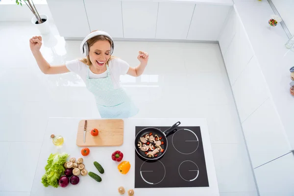 Hign hoek boven foto van huisvrouw besteden ochtend luisteren naar muziek moderne oortelefoons dansen hakken tomaten voor veganistische salade staande witte keuken binnen — Stockfoto