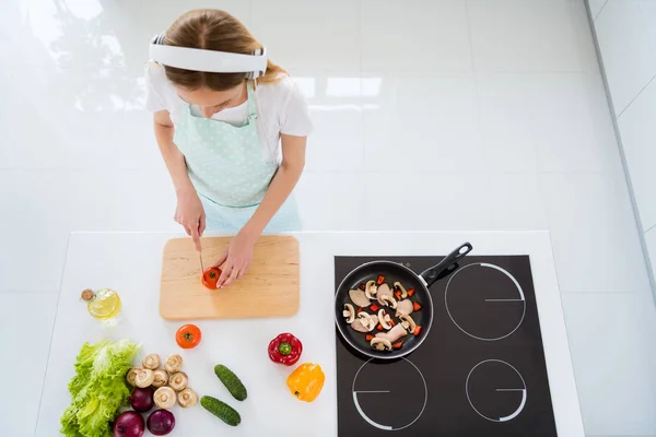 Hign hoek foto van huisvrouw besteden ochtend luisteren naar muziek moderne oortjes hakken tomaten voor veganistische salade staande witte keuken binnen — Stockfoto