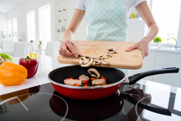 Cropped photo of housewife hands holding cutting wooden board checking meat condition adding fresh mushrooms cooking tasty dinner white light kitchen indoors — 스톡 사진